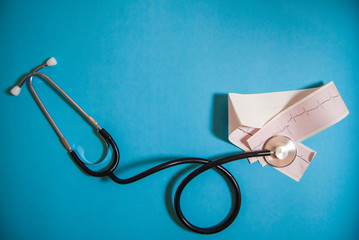 Stethoscope with a cardiogram on a blue monophonic background, used in medicine