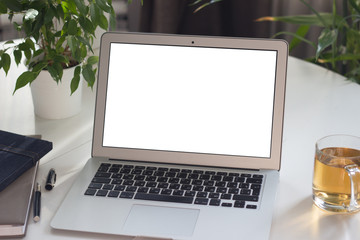  Laptop on white table on background of green plants