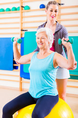 Senior woman with trainer doing fitness sport in gym