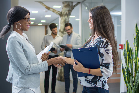 Two Businesswomen Shaking Hands In Modern Office.