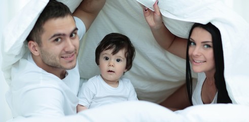 Obraz premium Families with children in bed under a blanket