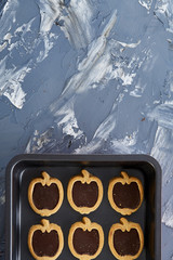 Fresh baked chocolate apple shaped cookies on a cookie sheet, top view, close-up, selective focus
