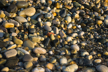 pebble stones on the sea beach, the rolling waves of the sea with foam