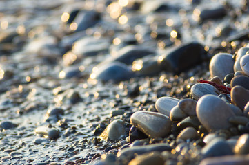 pebble stones on the sea beach, the rolling waves of the sea with foam