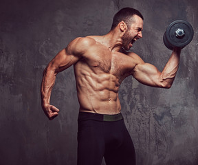 Brutal athletic bearded shirtless male doing exercise with dumbb
