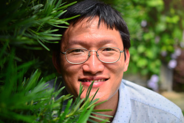 Chinese man smiling with natural green plant background.