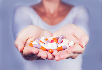 Hand holding a stack of many different pills