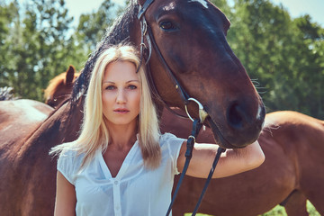 Obraz premium A charming woman standing with a brown horse.
