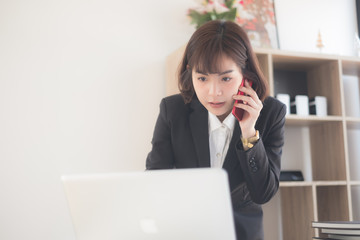 young beautiful asian woman talking on her phone with a client