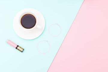 A cup of coffee and accessories on pastel background. Copy space