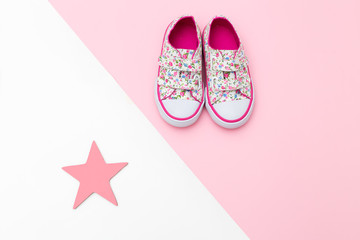 Sneakers for little girl and pink star on pastel background