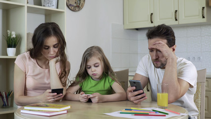 Obraz premium Family using gadgets at home ignoring each other, lack of live communication