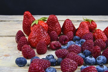 Healthy mixed fruit and ingredients with strawberry, raspberry, blueberry. Berries on rustic white wooden background. Free space for text. Copy space for banner