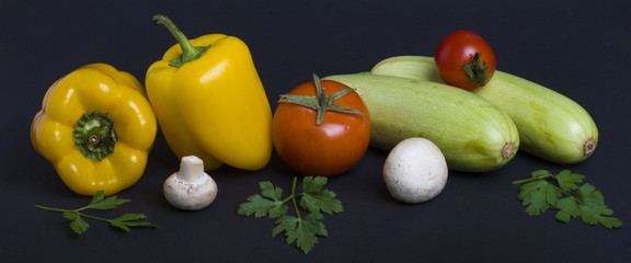 Fototapeta na wymiar Yellow peppers with zucchini and tomatoes on a dark background. Composition from different vegetables on a dark background. White mushrooms with peppers and tomatoes.