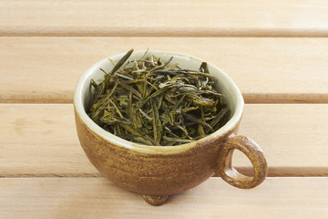Ceramic cup with leaves of green, wooden desk