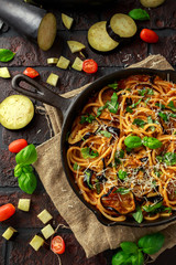 Vegetarian Italian Pasta Spaghetti alla Norma with eggplant, tomatoes, basil and parmesan cheese in rustic skillet pan.