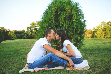 young romantic couple kissing on picnic in park