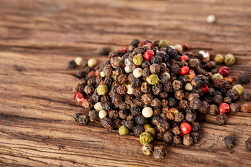 Top view on black, red and white peppercorns isolated on wooden background, shallow depth of field.