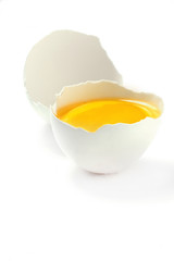 a half of raw hen egg with yolk in egg shell  over white background