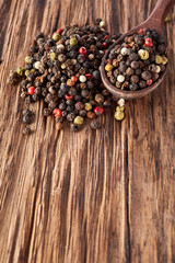 Top view on black, red and white peppercorns isolated on wooden background, shallow depth of field.