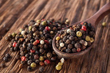 Top view on black, red and white peppercorns isolated on wooden background, shallow depth of field.