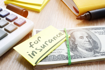 Memo with word for insurance on a stack of money.