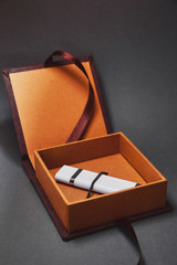 A dark brown box for USB flash drive with a cover made of suede is open with a flash drive inside. A beautiful stylish luxury gift package on a dark background. A gift for respectable wealthy people.