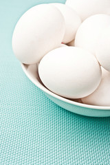 several white hen raw eggs in aquamarine green bowl plate like a concept for cooking, Easter and ingredients 
