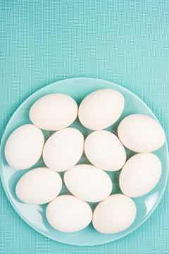 several white hen raw eggs in aquamarine green bowl plate like a concept for cooking, Easter and ingredients 
