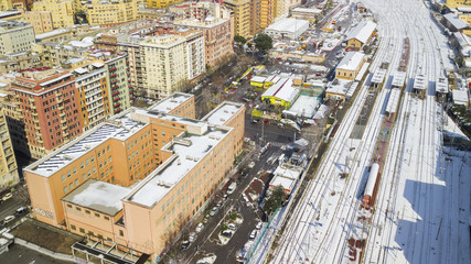 Fototapeta premium Aerial view of the Tuscolana station in Rome, Italy. Around the tracks there are the palaces and streets of the Italian city. The railroad tracks are made of steel. Everything is covered by snow.