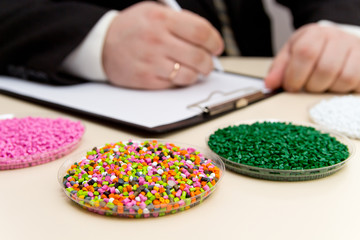 Businessman inspects plastic pellets for industry. Plastic raw materials in granules . Polymer,...