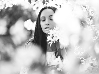 Beautiful young woman surrounded by flowers of apple-tree