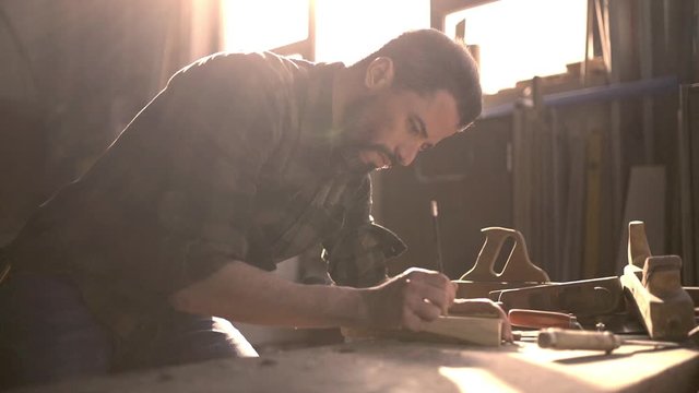 Handsome man in his fourties working with tools and wood at his workplace