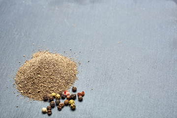 Top view on composition of peppercorns in wooden spoon on dark background, close-up.