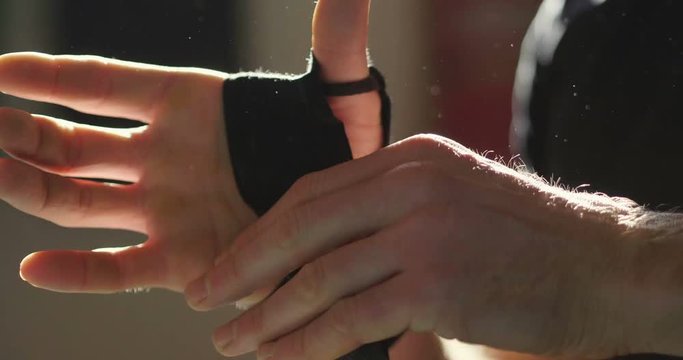 An athlete prepares for training in the gym, wraps his hands with professional bandages and then puts the magnesite on his hands. Concept of: sport, power, extreme, fitness.