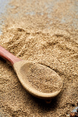 Top view of a wooden spoon full of grind black pepper, shallow depth of field.