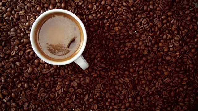 Top View Of Cup Of Black Coffe Put It On Coffe Beans Background. White Cup Of Black Coffee