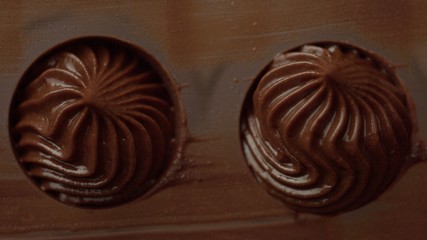 closeup of pastry bag filling candy mold form with chocolate cream Top view macro