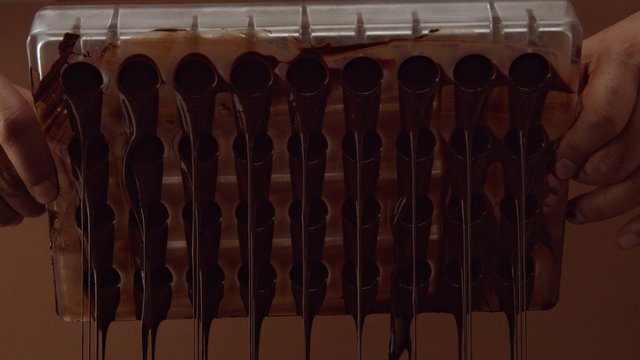 chocolate candy mold form in process of creating candys. liquid chocolate falling down from candy mold