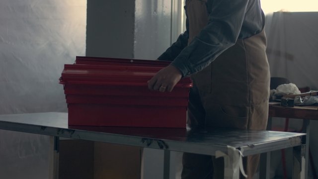 worker in his garage with a red tool storage box preparing for work