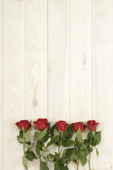 Fototapeta na wymiar Rosas de color rojo sobre fondo de madera blanca