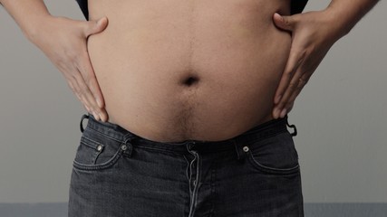Naklejka premium overweight man closeup of belly front view. put up shirt and pinch and clap a belly