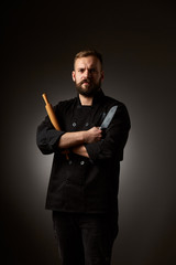 Chef cook holds a knife over dark grey background