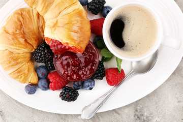 Delicious breakfast with fresh croissants and ripe berries and jam