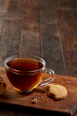 Cup of tea with cookies on a cutting board on a wooden background, top view
