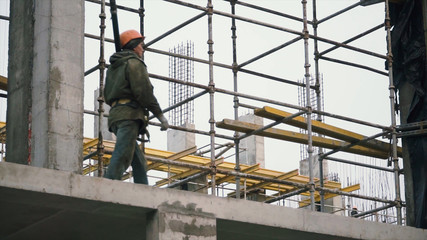 Construction workers on site holding pipe. Clip. A man goes with a pipe at the construction site