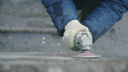 Builder worker with grinder machine cutting finishing concrete wall at construction site. Clip....
