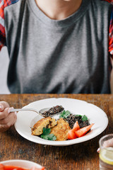 Woman eating vegetarian food (black quinoa and cutlets from oatmeal and prunes). Healthy vegetarian food concept