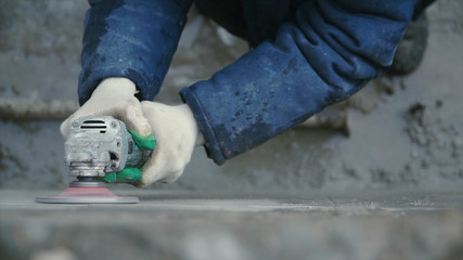 Builder worker with grinder machine cutting finishing concrete wall at construction site. Clip....