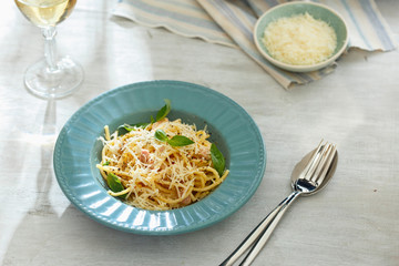 Plate carbonara with glass of white wine on white wooden table. Dinner table